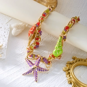 Detail of bohemian gold chain necklace with colorful starfish and shell pendants