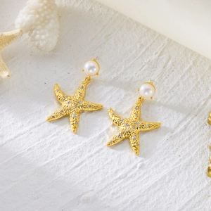 Detailed view of starfish earrings with pearls and crystals on a white stone base