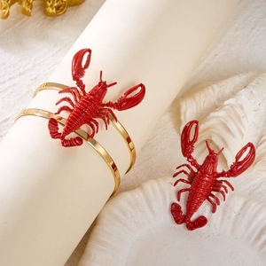 Detail of red lobster napkin rings with gold metal base on an elegant ocean-themed table
