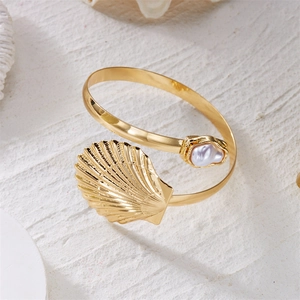 Detail of golden bohemian shell arm cuff featuring a baroque pearl and starfish element