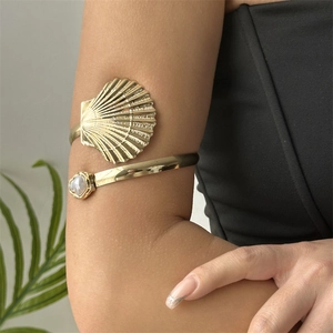Detail of bohemian gold shell arm cuff featuring a white pearl and embossed texture