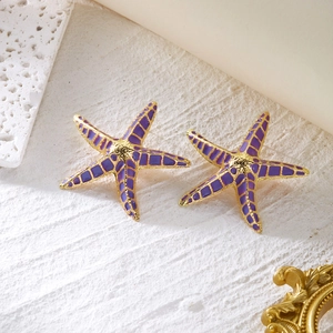 Macro detail of Bohemian purple enamel starfish earrings with a golden metal frame