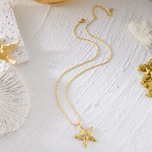 Detail of a golden starfish necklace with shimmering zircons on an ocean-themed background