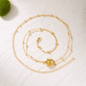 Détail d'une chaîne de corps dorée avec pendentif fleur 3D et fermoir mousqueton ajustable