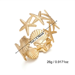 Detailed macro view showing the textured starfish and shell motifs on gold sea bangle