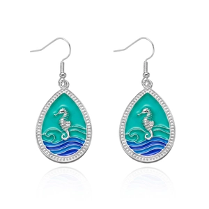 Macro shot of silver teardrop earrings with seahorse enamel and sparkling crystals