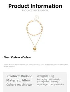 Detailed view of layered gold necklace with shell and scallop pendants on white background