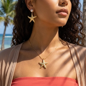 Starfish jewelry set with pearls and rhinestones on model at tropical beach background
