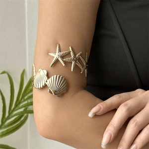 Detailed view of bohemian gold ocean arm cuff with starfish and shell elements on arm