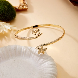 Detail of gold starfish and crab arm cuff on a ceramic plate for beach vacation style
