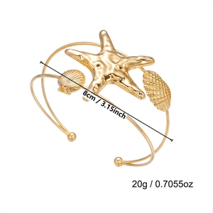 Macro detail of golden starfish and seashell cuff bracelet showing 8cm diameter and 20g weight