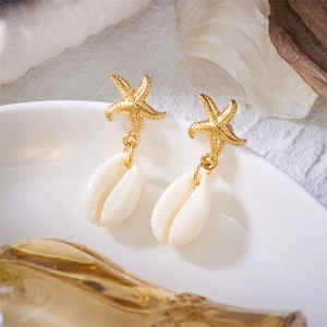 Detailed macro view of golden starfish earrings with polished white shell pendants