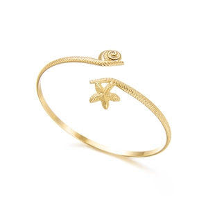 Detailed macro view of golden starfish and seashell textures on an open cuff bracelet
