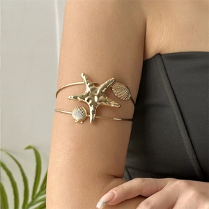 Detail of gold seashell starfish upper arm cuff with hammered metal texture on arm