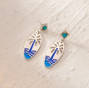 Detail view of silver drop earrings with turquoise beads and blue ocean palm tree motifs