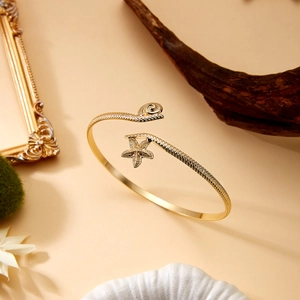 Detail of a golden open starfish and seashell arm cuff bracelet for beach vacations