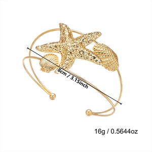 Detail of bohemian gold arm cuff featuring starfish and seashell with size specifications