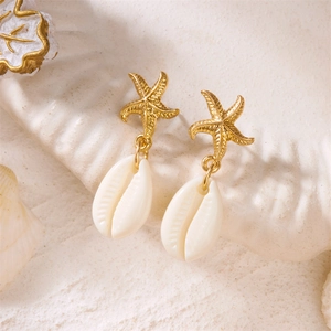 Close-up of gold starfish earrings with white seashell pendants and textured metal detail