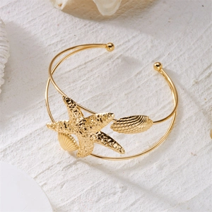 Detail of golden bohemian arm cuff with textured starfish and shell elements