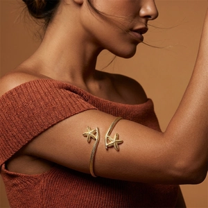 Detailed view of a gold starfish arm cuff with realistic texture on a female model arm