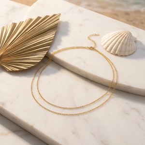 Detail einer zwelagigen goldenen Taillenkette mit Kristallen auf Marmorhintergrund