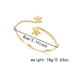 Detail shot of golden starfish open arm cuff showing 8cm diameter and textured finish