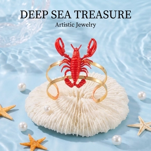 Detailed view of red lobster open bangle with gold finish on aquatic background