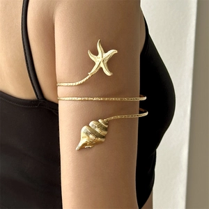 Detailed shot of golden spiral armlet featuring intricate starfish and seashell ornaments