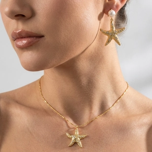 Close-up of golden starfish necklace and pearl earrings with zircon on model
