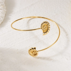 Detail of a golden bohemian arm cuff featuring textured spiral seashell ornaments