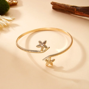 Detailed shot of warm gold starfish arm cuff with textured twisted rope band design