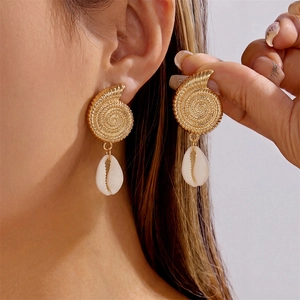 Detailed view of bohemian gold conch earrings featuring white shell pendants