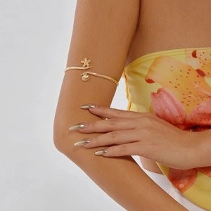 Detail of a golden starfish and seashell armlet worn on arm with floral clothing