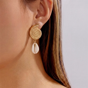 Detailed close-up of golden nautilus shell earrings with white natural shell drops on a model