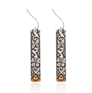 Detail view of vintage silver drop earrings with floral engravings and amber heart gems