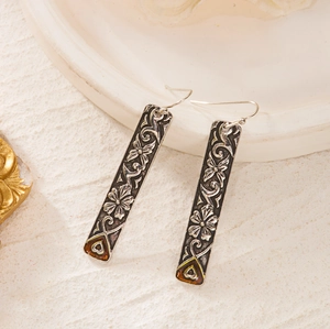 Macro view of vintage silver rectangle earrings with flower and butterfly engravings