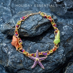 Detail of bohemian ocean-themed jewelry with starfish and shell charms on rocks