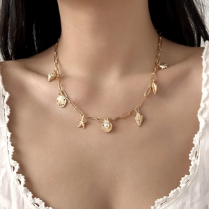 Detail of layered gold necklace featuring seashell, starfish charms and a white pearl