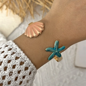 Detail of bohemian gold open bangle with pink shell and turquoise starfish charms