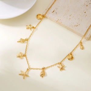 Detail of gold shell and starfish charms on a beach-style layered necklace