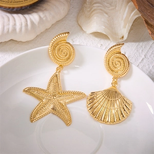 Detailed close-up of golden asymmetric earrings with starfish and shell charms