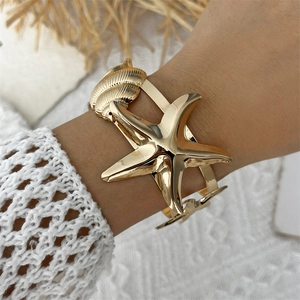Golden ocean cuff bracelet with starfish and seashell on a model's wrist