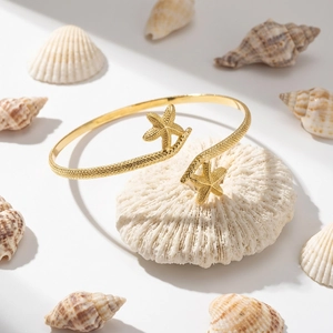 Detailed close-up of golden starfish arm cuff resting on white coral with sea shells