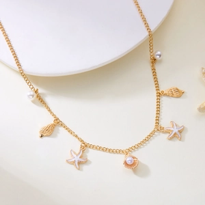 Detail of gold shell necklace with white pearls and enamel starfish charms on a white stand