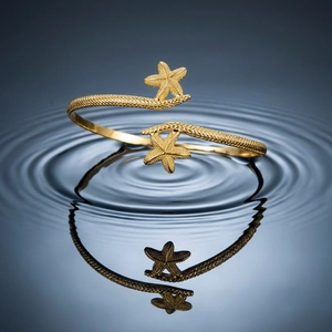 Detailed macro view of gold starfish arm cuff with granular texture on water ripples
