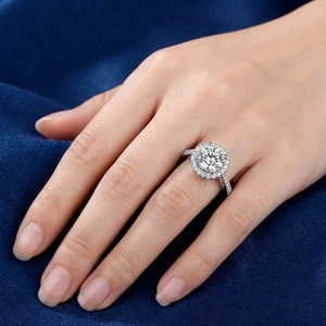 Classic round halo engagement ring with pavé diamond band on a finger for women