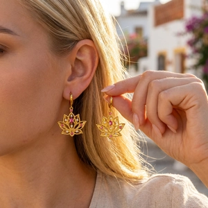 Boho hollow lotus earrings in gold finish with pink gemstones worn by a female model