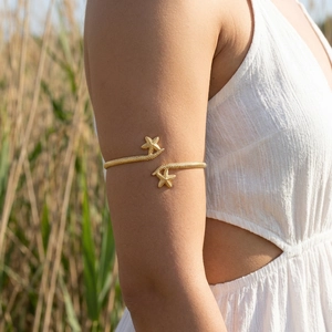 Detailed close-up of golden starfish arm cuff with textured finish on a model's arm