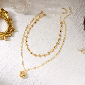 Detail of gold double-layer necklace with shell pendant and lobster clasp for beach style