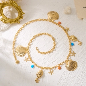 Détail de breloques coquillage et étoile de mer sur une chaîne de taille dorée avec perles